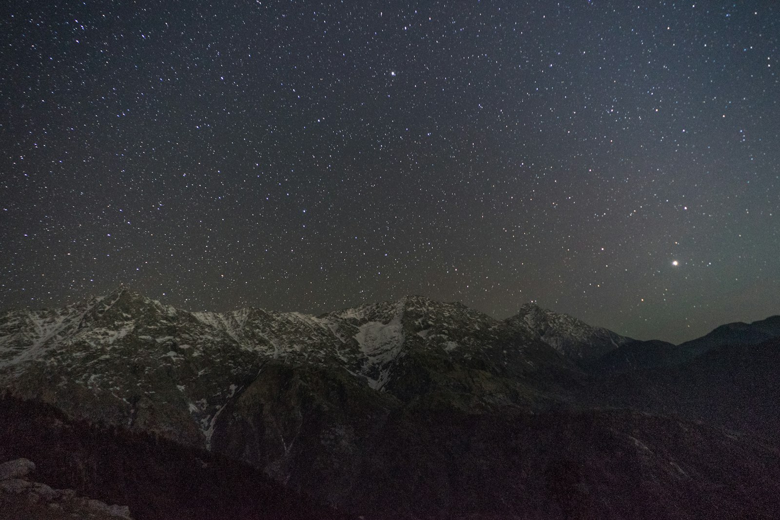 Layered mountain ridges silhouetted beneath a dense field of stars